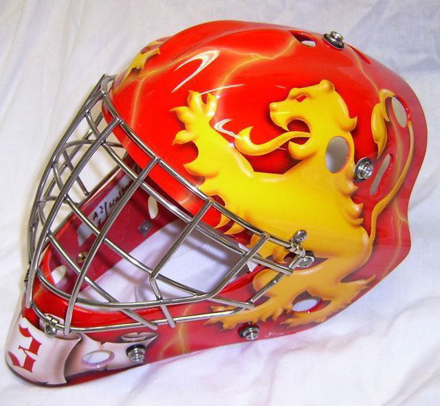 A vibrant red and yellow hockey goalie mask with a dragon design.