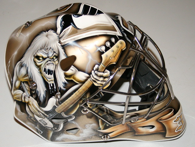 Custom hockey goalie mask with a fierce skeleton and guitar design.