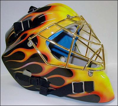 A vibrant hockey goalie mask with yellow and black flame design.