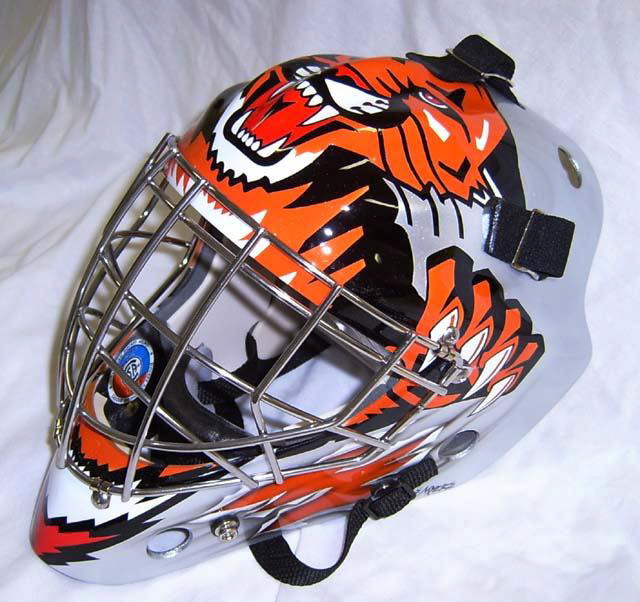 Hockey goalie mask with fierce tiger design and protective cage.