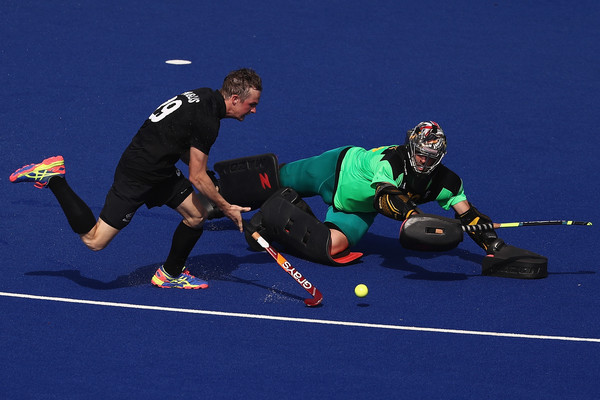 Field hockey players competing intensely for the ball on a blue turf.