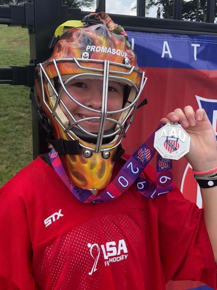 Young athlete in protective helmet proudly holding a medal.