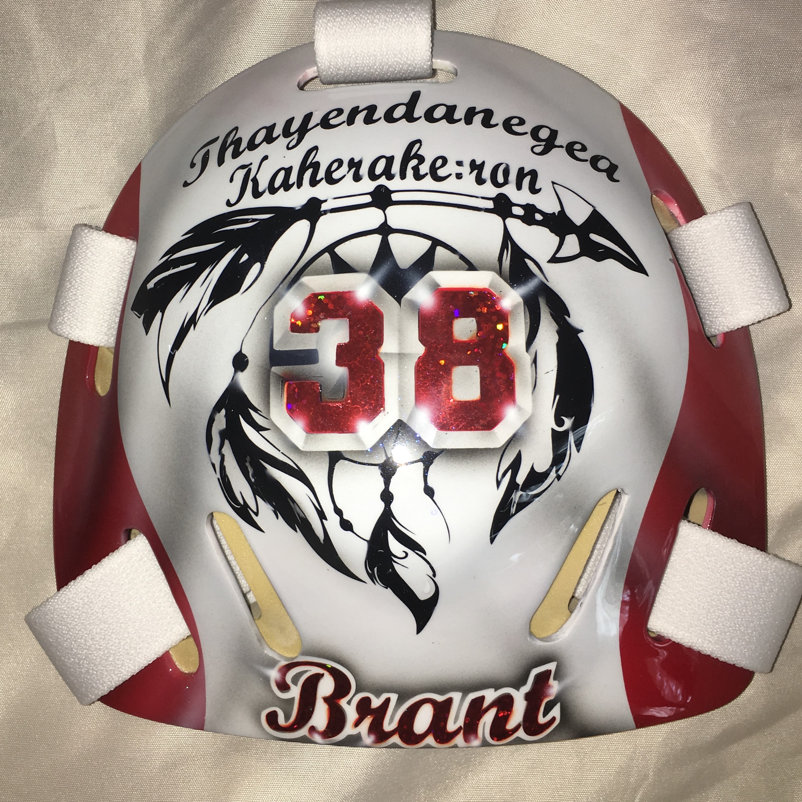 Custom white hockey goalie mask with red and black design.