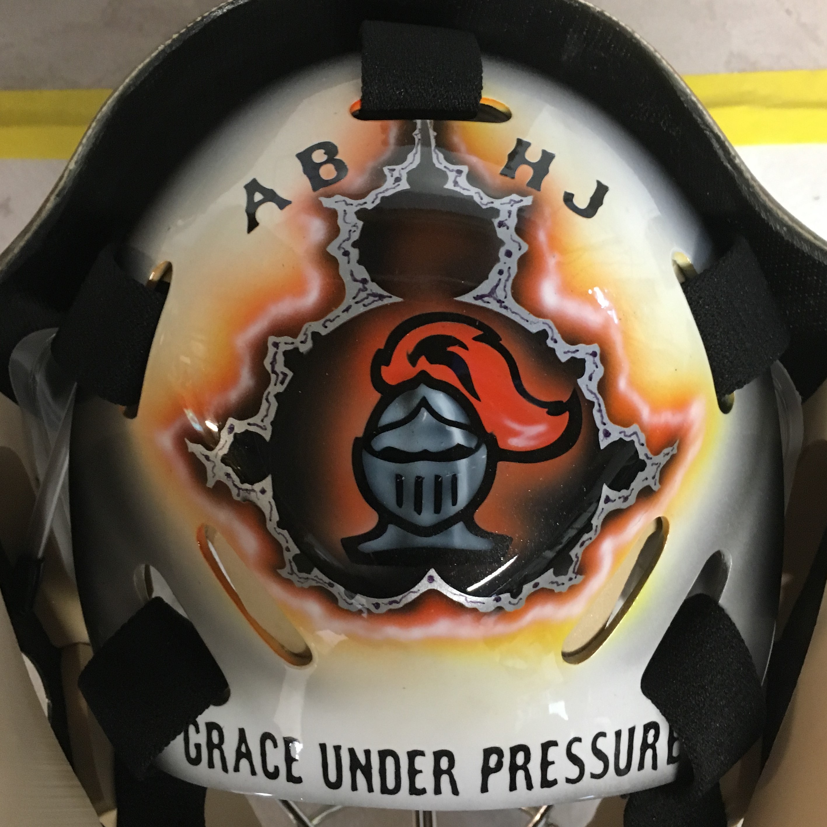 A helmet featuring a knight's helmet design with the phrase 'Grace Under Pressure'.
