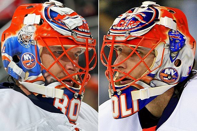 Two hockey goalies wearing red, white, and blue masks face each other intensely.